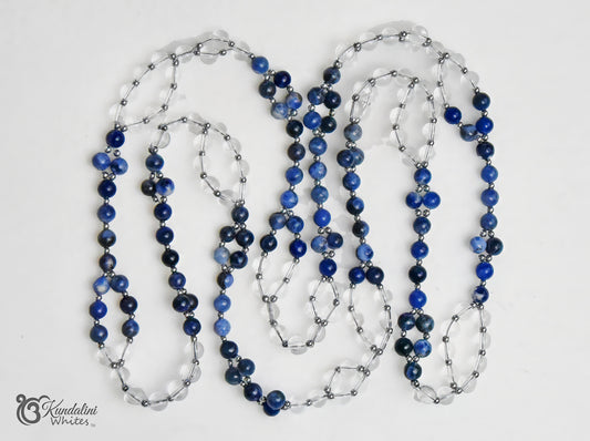 A Tantric necklace of sodalite and clear quartz beads, separated by small silver metallic spacers. The necklace is laid out in loops on a plain white background with a 'Kundalini Whites' watermark in the bottom-left corner.