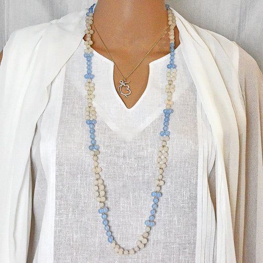 Person wearing a long aquamarine and white jade tantric mala.