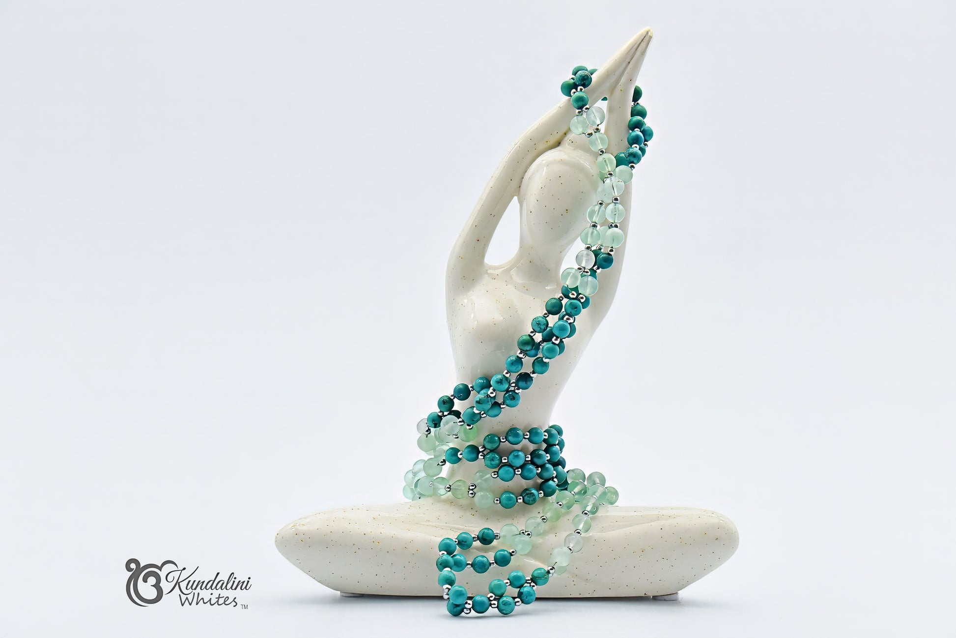 Turquoise beaded tantric necklace draped over a white ceramic figure on a white background