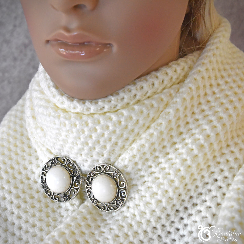 Close-up of a mannequin wearing a white knitted sweater with a decorative brooch.