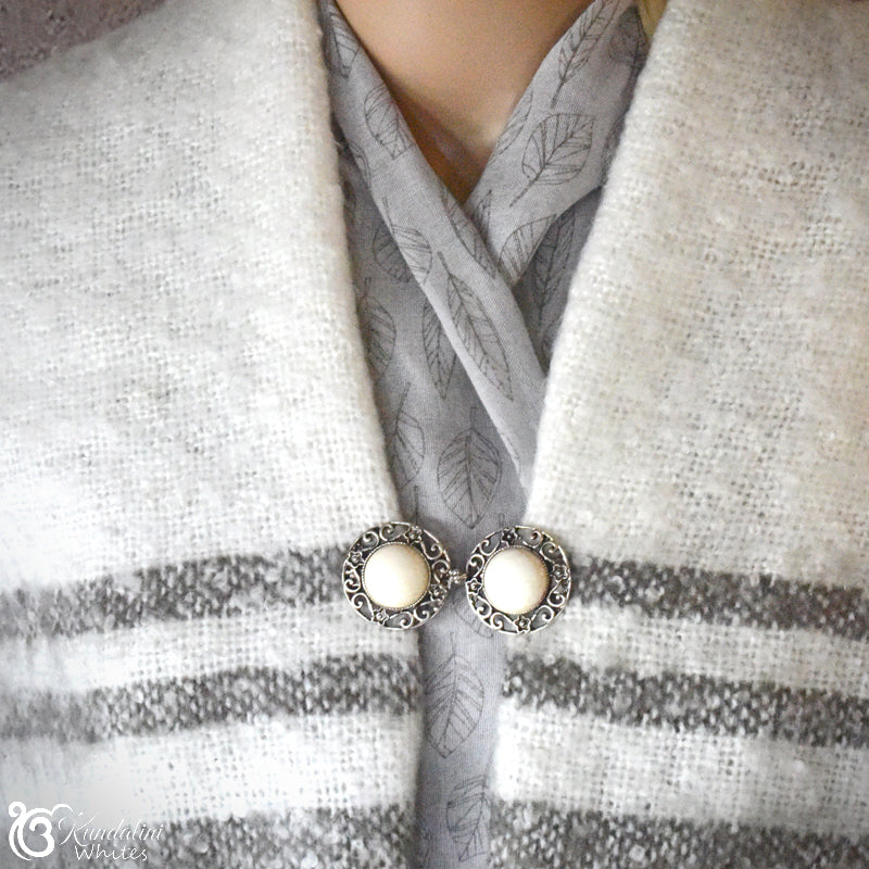 Close-up of a scarf with a brooch and earrings on a neutral background