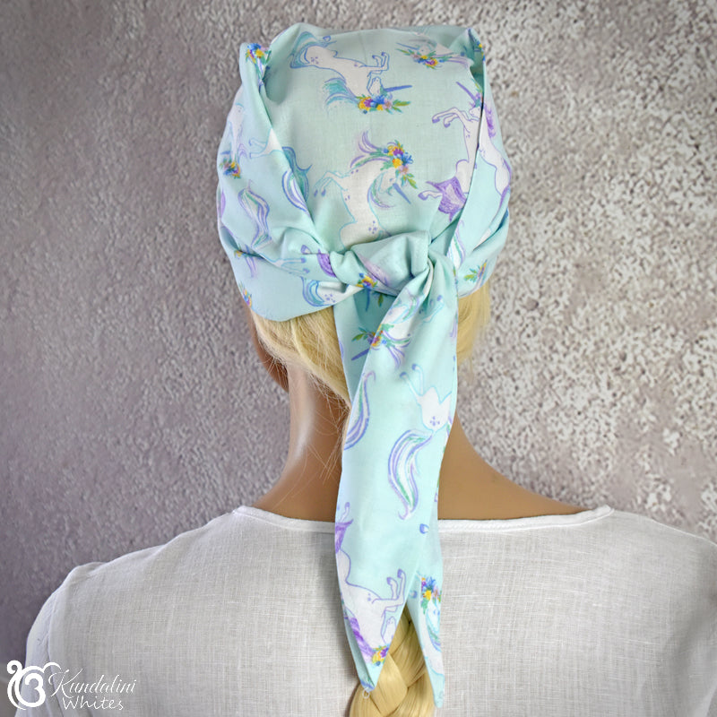 Person wearing a light blue headscarf with unicorn pattern against a neutral background