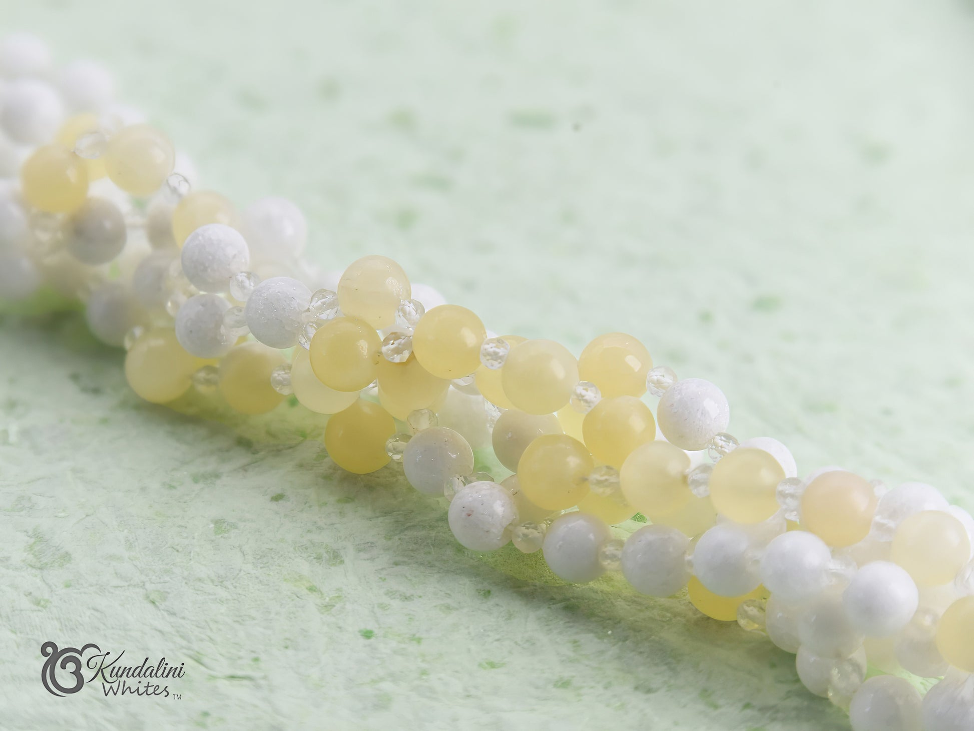 Close-up of a white and yellow tantric necklace on a light green background