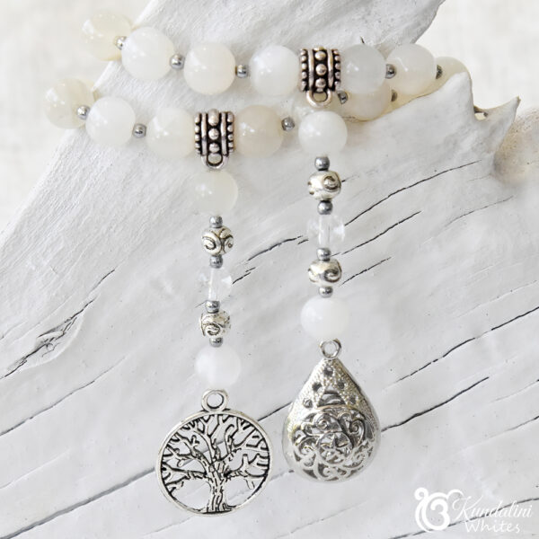 Detailed look at Tree of Life and hollow droplet pendants on a moonstone mala