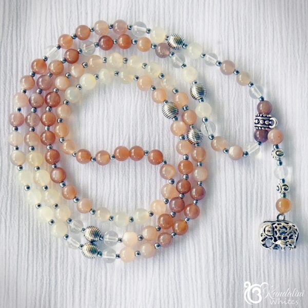Moonstone mala 108 curled up on white ceramic surface