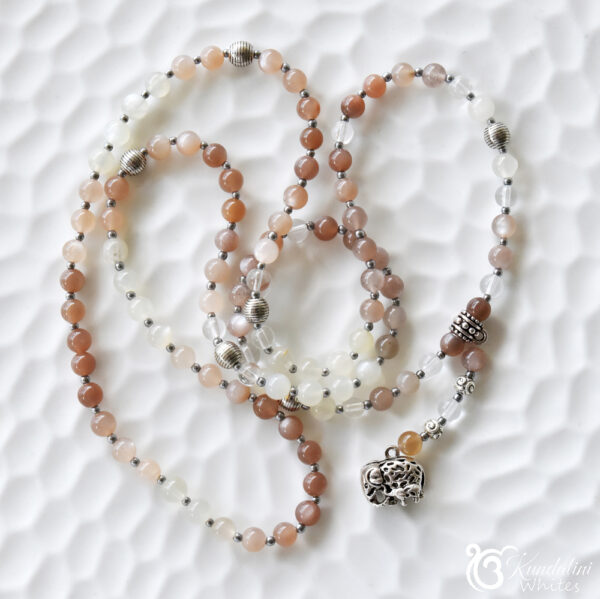 Warm earthy gemstone mala 108 on white ceramic surface