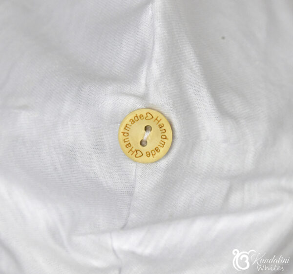 Top view of white beanie with 'handmade' button in the middle